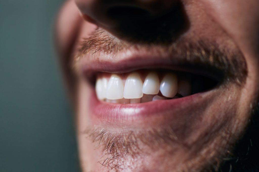 Toothy smile of young man. Close-up view of white teeth.